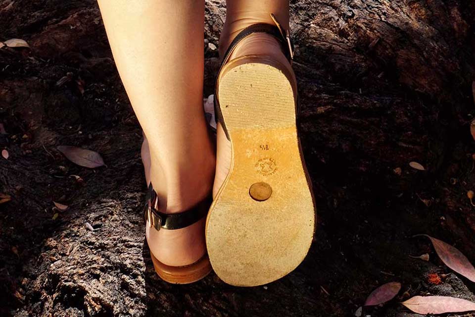 Person wearing earthing sandals with conductive grounding plug sole outdoors
